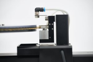 Close-up of the MTT690 tensile tester, where a crimped hair sample has been clamped and the instrument is preparing to take a tensile measurement