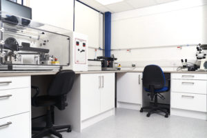 Dia-Stron's natural and synthetic fibre laboratory. Instruments including the FTT950 torsion tester in an ETS chamber are arranged on an L-shaped worktop with 2 chairs tucked underneath